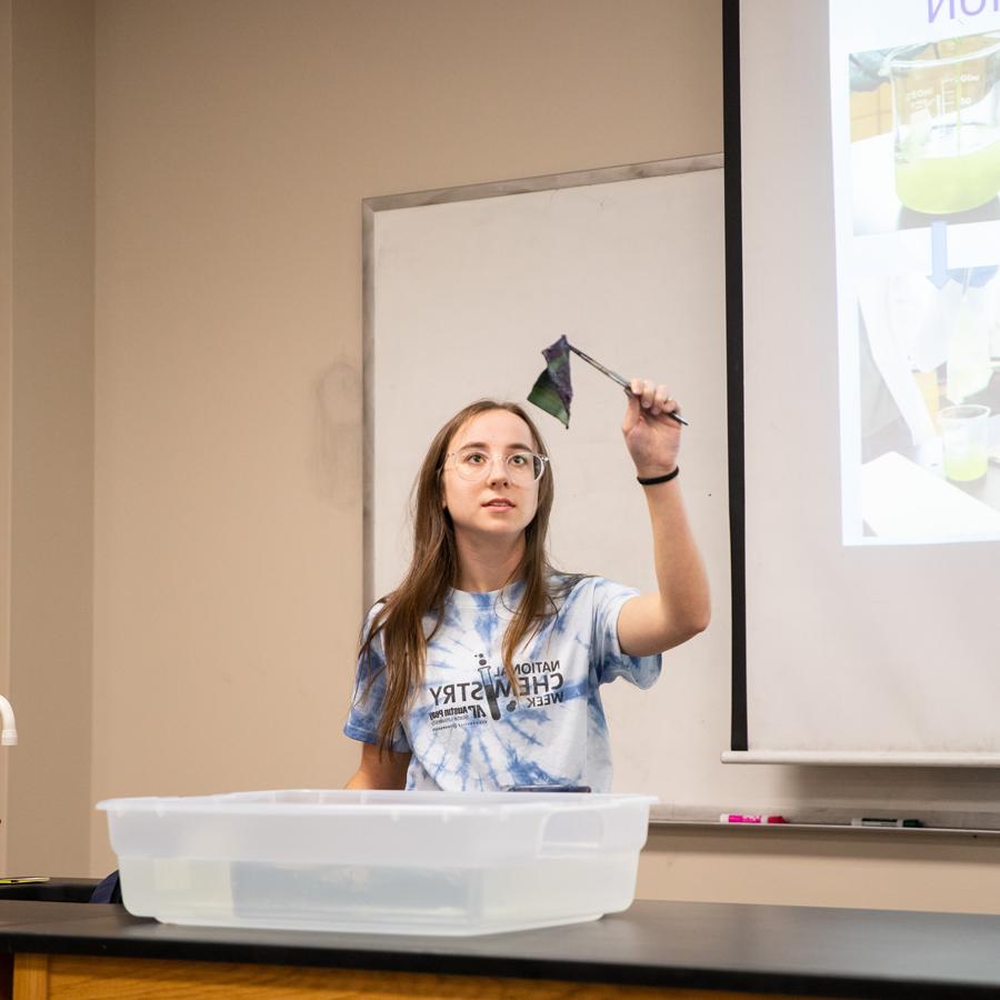 Student holding up a piece of fabric with tweasers